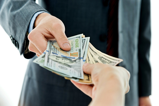 Closeup of businessman hands giving money.