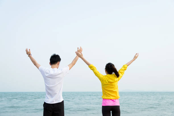 istock Young couple with their hands raised on beach 841920102