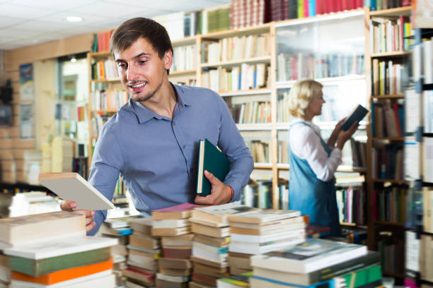 istock Young laughing man choosing new book from many 841930578