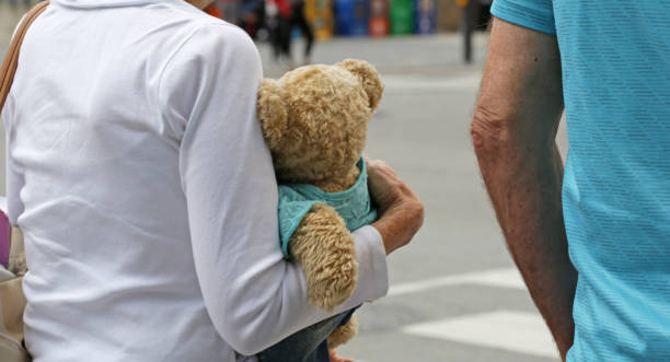 Toronto, Canada - August 19, 2017: Grandparents walk with a teddy bear through Toronto's South Core neighbourhood in summer. Front Street West.