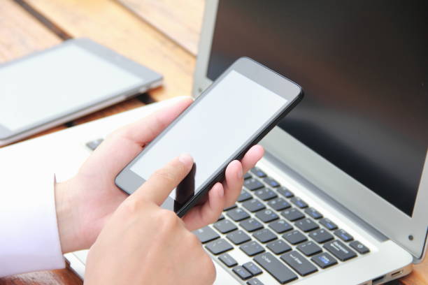istock Woman using mobile phone with laptop outdoors 841935044