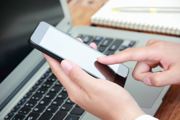 istock Woman using mobile phone with laptop outdoors 841935078