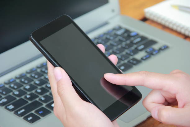 istock Woman using mobile phone with laptop outdoors 841935162