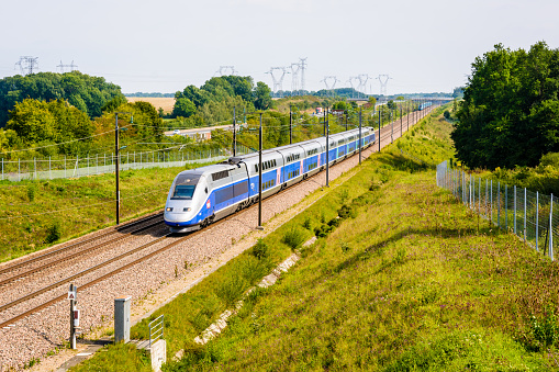 Moisenay, France - August 23, 2017: A double-decker TGV Duplex high speed train in Atlantic livery from french company SNCF driving on the Southeast TGV line along the A5 highway in the countryside.