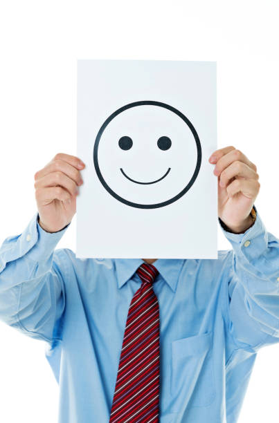 Businessman holding paper with smiley face against white background.