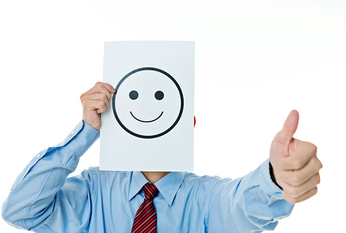 Businessman holding paper with smiley face against white background.