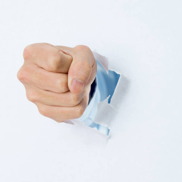 istock Man's fist punching through white paper 841944066