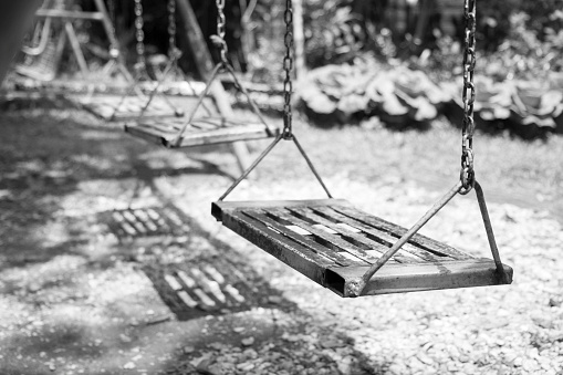 Empty swings on playground.wings in city park. Empty chain swings in summer kids children playground.