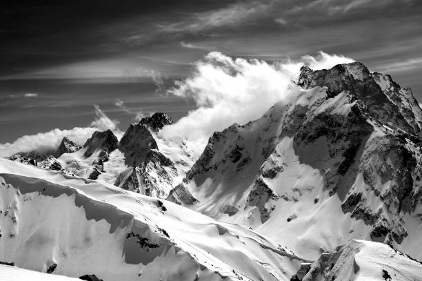 istock Black and white winter mountains with snow cornice and cloudy sky in nice sun day 841949112
