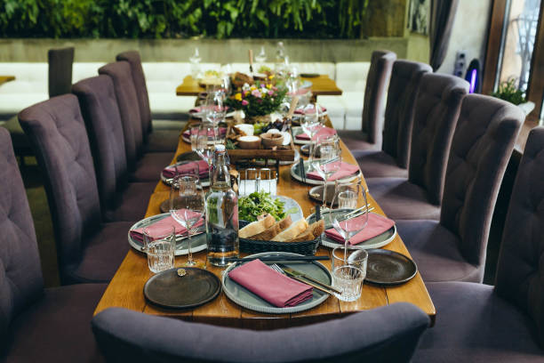 istock Long festive table served dishes and decorated with branches of greenery on a background. Gray chairs for guests and cutlery with food on the table. Wedding banquet. 841954070