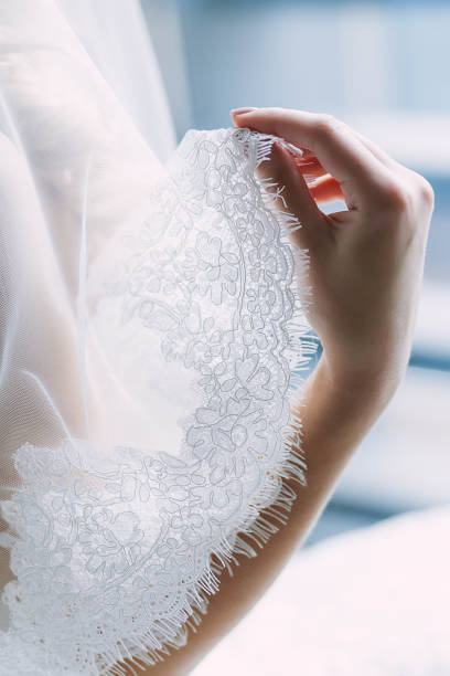 istock Elegant bride's hand with a white lace veil. Artwork Wedding concept. Close-up, soft focus 841955230