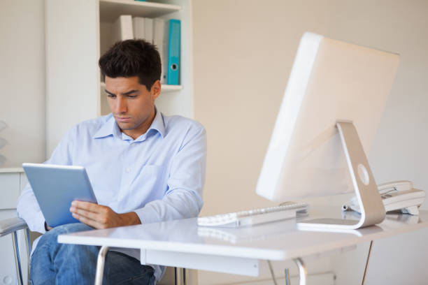 istock Casual businessman using his tablet at his desk 841955606