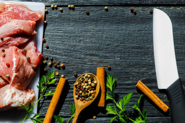 istock Fresh meat, turmeric, spice, ceramic knife on a black wooden background 841965030