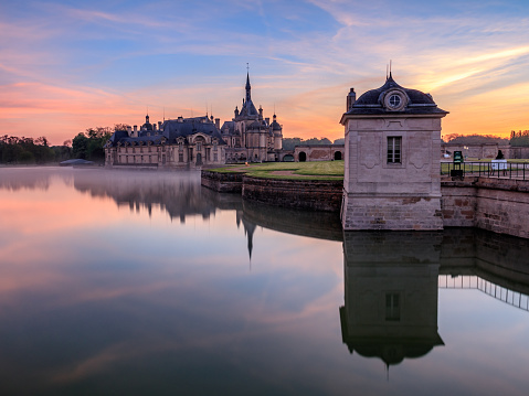 Dawn on the castle of Chantilly with the colors of the sunrise. Photo taken from outside the castle from the road to the rim