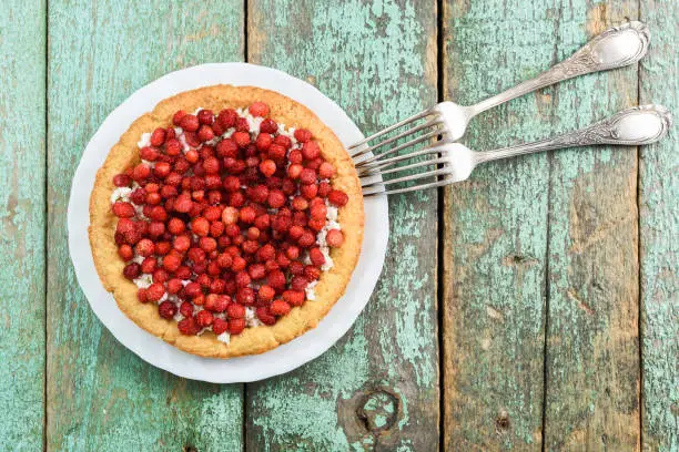 Fresh forest strawberry tart with cottage cheese with vintage melchior forks overhead view