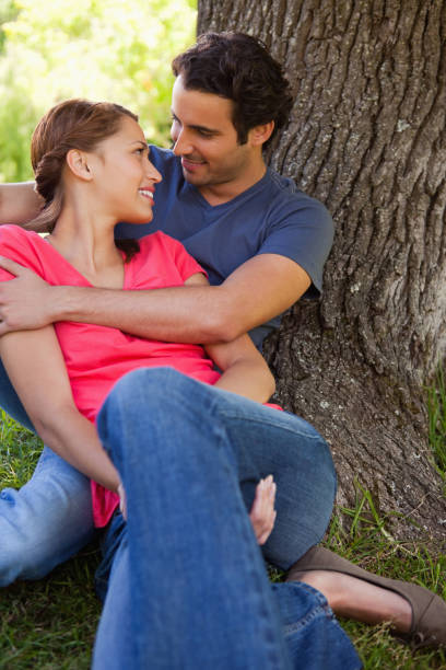 istock Man looking at his friend as he holds her while they sit together in the shade 841991864