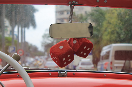 Fuzzy red dice on a vintage red car in Havana
