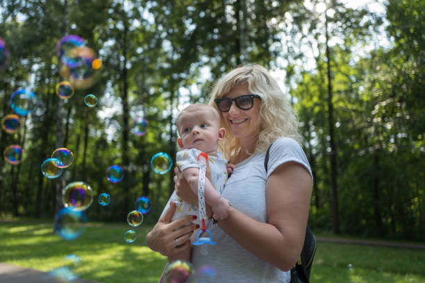 istock Child in mother's arms looking to the soap bubbles 841994410