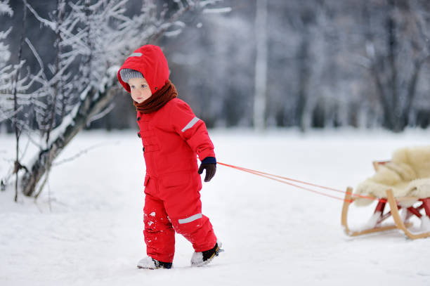 istock Little boy in red winter clothes with toboggan 841997572