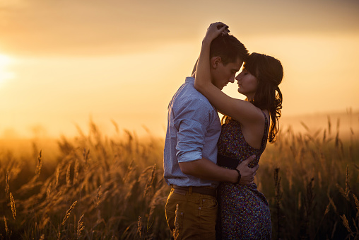 Loving couple in field at sunrise