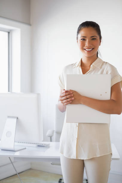 istock Casual businesswoman smiling at camera holding folder 842001434