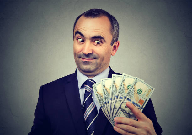 funny sly business man holding looking at money - greed imagens e fotografias de stock