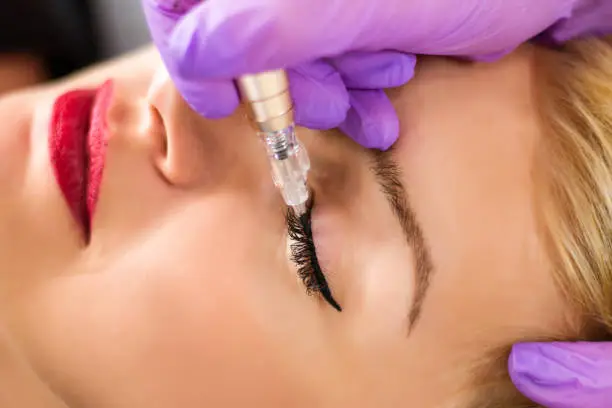 Photo of Permanent make up eyeliner procedure in beauty studio, close up