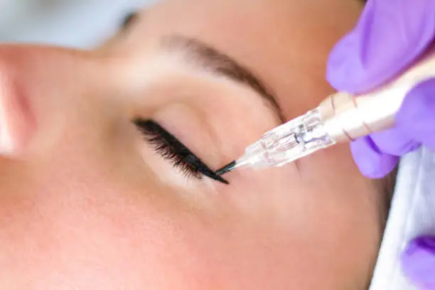 Photo of Young beautiful woman making permanent makeup in cosmetology salon, close up