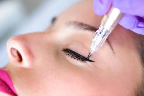 Photo of Permanent make up eyeliner procedure, applying on young girl, close up