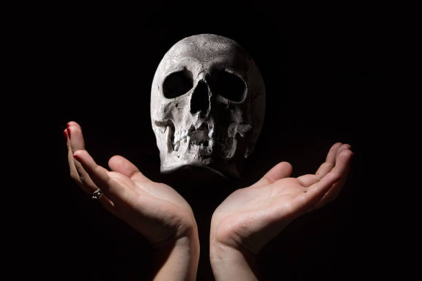 istock Black magic concept. Human skull between woman hands on black background. 842070964