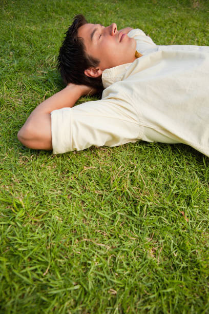istock Man lying in grass with his eyes closed and both hands behind his head 842081876
