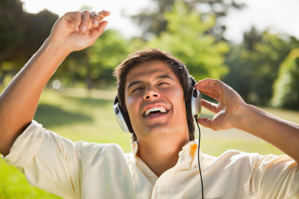 istock Man raising his arms while using headphones to sing along to music 842081976