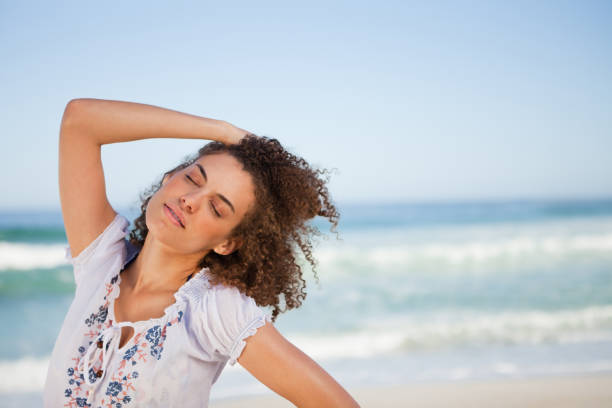 istock Young woman closing her eyes while standing on the beach 842089470