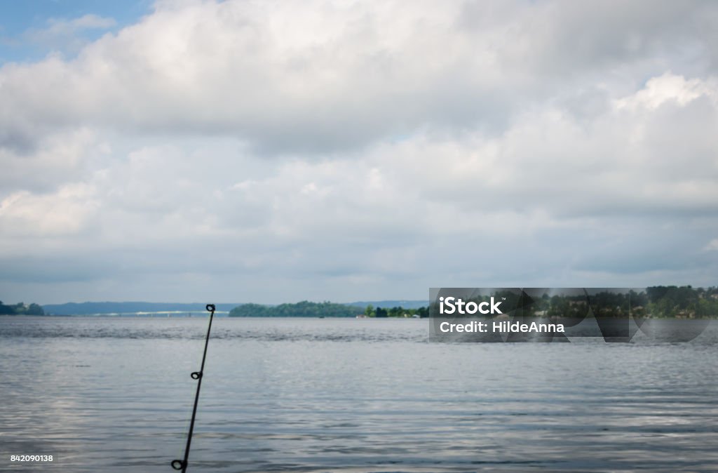 Fishing and boating on Tennessee River, Lake Guntersville, AL Fishing and boating on the Tennessee River, Lake Guntersville, AL. Fishing pole extended to cloudy sky with scenic backdrop. Enjoying relaxing outdoor activity. Lake Stock Photo