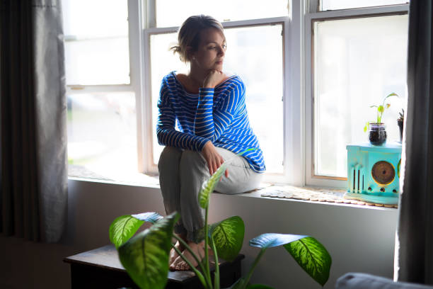 istock Beautiful young woman sitting near window 842094042