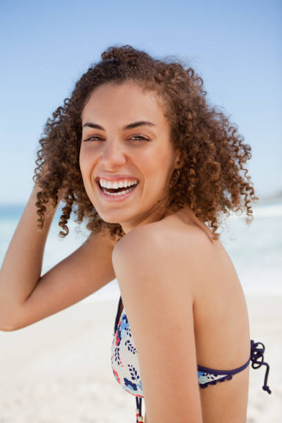 istock Young woman wearing a bikini while smiling and standing on the beach 842096556