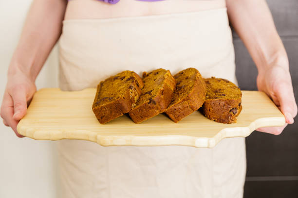 istock Young woman holding sliced pumpkin bread loaf 842100956