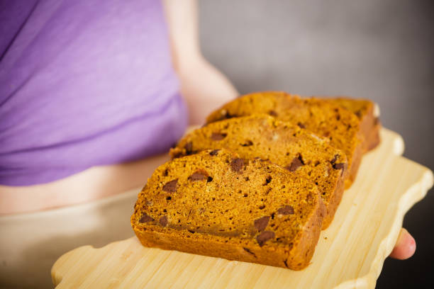istock Young woman holding sliced pumpkin bread loaf 842101078