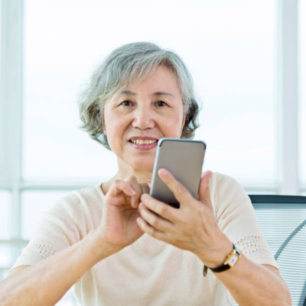 istock Cheerful senior woman text messaging on mobile phone at home 842112106