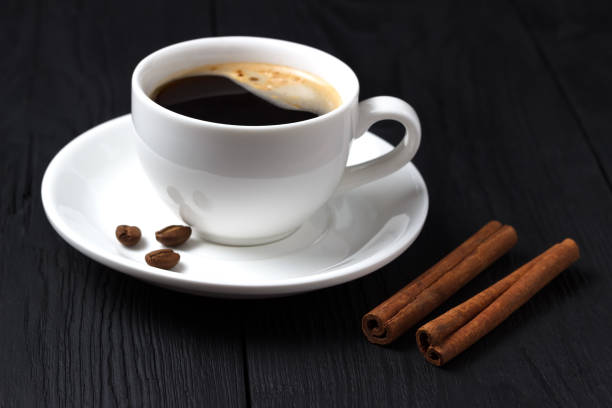 istock Black coffee in a white cup with cinnamon and foam on a black wooden background 842119914
