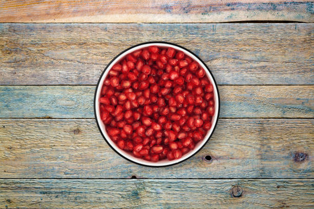 istock Pomegranate seeds bowl on wood background from directly above 842126594