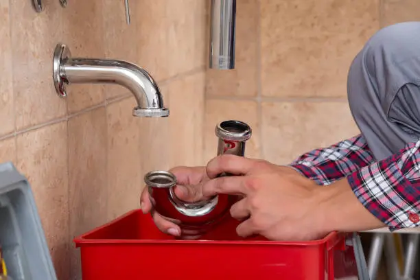 Close-up Of Plumber's Hand Fixing Sink In Bathroom