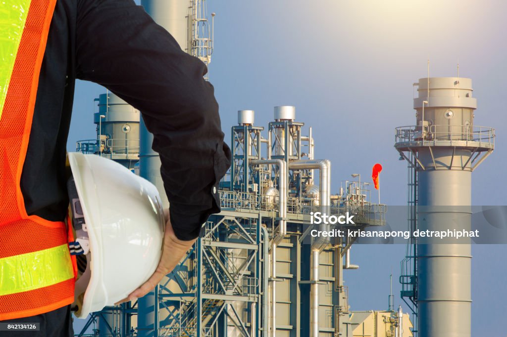 engineering man with white safety helmet standing in front of oil refinery building structure in heavy petrochemical industry Blue Stock Photo