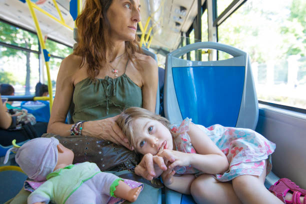 little girl lying on mother legs on the bus stock photo