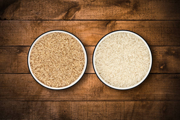 White and unpolished brown basmati rice in circle bowls on a rustic old wood background, shot from directly above. Clipping path included.