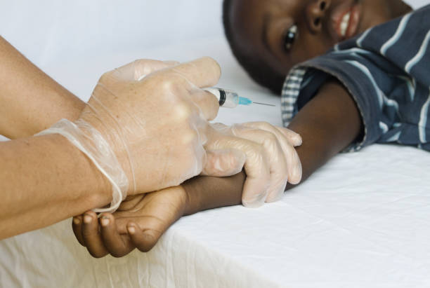 African black boy getting a vaccination from a white medical doctor stock photo