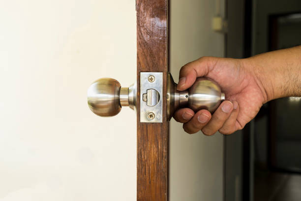 l'uomo tiene la manopola d'argento dall'interno di casa per uscire - può utilizzare per visualizzare o montaggio sul prodotto - keyhole door wood office foto e immagini stock