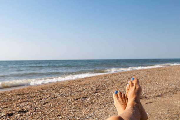 concetto di vacanza, piede femminile beato con smalto blu vicino al paesaggio marino - sole of foot human foot women humor foto e immagini stock