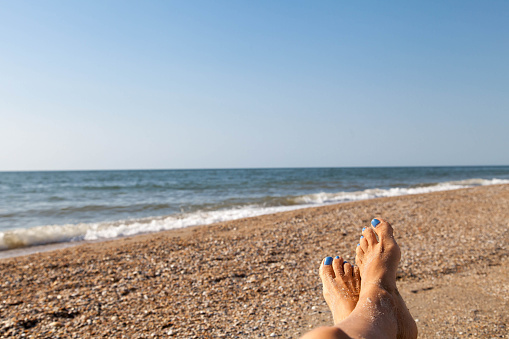Vacation concept, beatiful women foot with blue nail polish near sea landscape