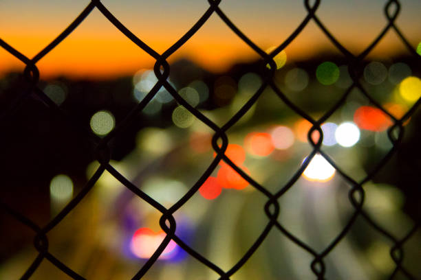 istock Wire mesh (mesh fence) with city road highway at dusk 842152526